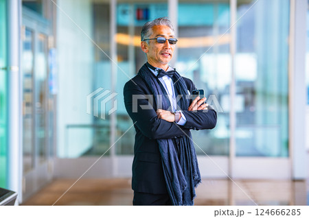 施設の自動ドアから屋外に出てくるタキシードを着た紳士 施設の自動ドアから屋外に出てくるタキシードを着た紳士 124666285