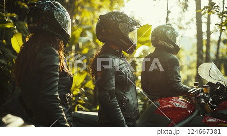 women motorcyclists riding through lush forest 124667381