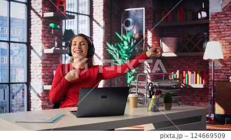 Female freelancer using ambience music on headphones to solve her tasks efficiently, working at home and multitasking with audio experience. Mature woman enjoying remote job. Camera B. Female freelancer using ambience music on headphones to solve her tasks efficiently, working at home and multitasking with audio experience. Mature woman enjoying remote job. Camera B. 124669509