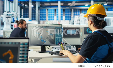 Solar panels manufacturing plant technician uses CAD program to optimize layouts. Photovoltaics factory staff member doing arrangements for maximum renewable energy output, camera A 124669555