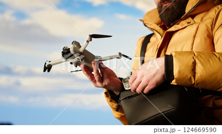 Modern traveler creating content and filming the valley with his drone, climbing on top of a high altitude mountain range. Hiker enjoying the landscape scenery, remote control. Camera B. 124669590