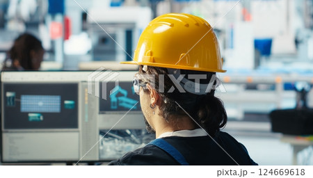 Photovoltaics factory engineer wearing yellow hardhat analyzing data, reviewing system metrics. Solar panels plant technician troubleshooting technical issues using computer software, camera B Photovoltaics factory engineer wearing yellow hardhat analyzing data, reviewing system metrics. Solar panels plant technician troubleshooting technical issues using computer software, camera B 124669618