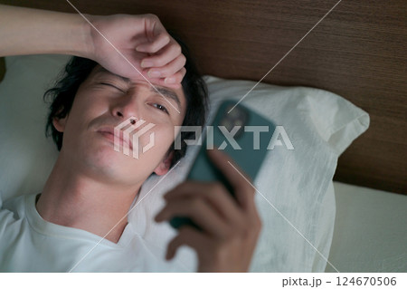 ベッドでスマホを見る男性 ベッドでスマホを見る男性 124670506