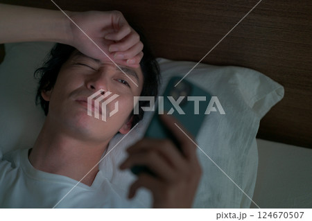 ベッドでスマホを見る男性 ベッドでスマホを見る男性 124670507