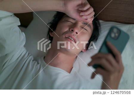 ベッドでスマホを見る男性 124670508