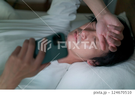 ベッドでスマホを見る男性 ベッドでスマホを見る男性 124670510