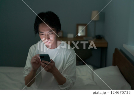 暗い部屋の中でスマホを操作する男性 124670733