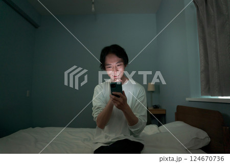 暗い部屋の中でスマホを操作する男性 暗い部屋の中でスマホを操作する男性 124670736