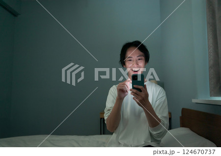 暗い部屋の中でスマホを操作する男性 暗い部屋の中でスマホを操作する男性 124670737