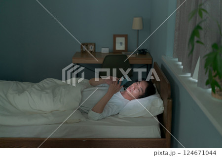 ベッドの中でスマホを操作する男性 124671044
