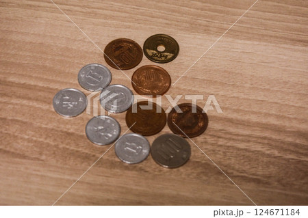 a group of Japanese yen coins in value one, one hundred, ten and five dollars on a wooden table with copy space 124671184