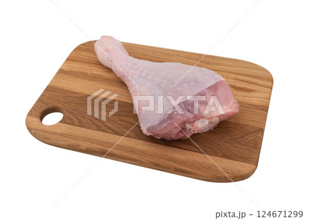 Raw turkey drumstick on wooden board isolated on white background. Turkey leg isolated. Raw turkey drumstick on wooden board isolated on white background. Turkey leg isolated. 124671299