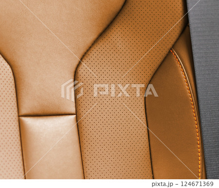 Car brown leather interior. Part of brown leather car seat details with white stitching. Interior of prestige car. Comfortable perforated leather seats. Perforated leather. 124671369