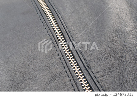 Macro shot of zipper on black leather texture background with stitching. Close-up of black leather material 124672313