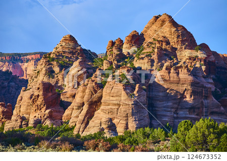 Red Rock Formations at Golden Hour with Lush Vegetation and Clear Sky 124673352