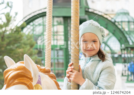 Little happy cute girl riding on carousel horse in park. Little girl have fun on carousel. Little happy cute girl riding on carousel horse in park. Little girl have fun on carousel. 124674204