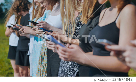 Teenage high school students addicted to technology and social media, using smartphones outdoors in summer 124674848