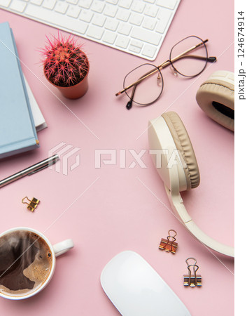 Pink workspace with keyboard, headphones, glasses, coffee, mouse, notebook and cactus plant Pink workspace with keyboard, headphones, glasses, coffee, mouse, notebook and cactus plant 124674914