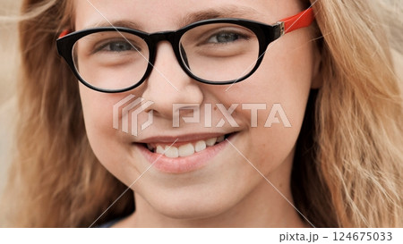 Smiling schoolgirl wearing glasses, radiating joy and self assurance with friendly expression Smiling schoolgirl wearing glasses, radiating joy and self assurance with friendly expression 124675033