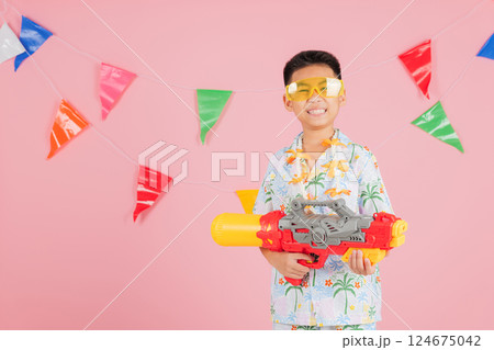 Songkran fun as a child with glasses and a floral shirt holds a water gun Songkran fun as a child with glasses and a floral shirt holds a water gun 124675042