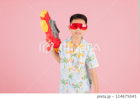 Songkran holiday fun as an Asian kid in a floral outfit and glasses holds a water gun Songkran holiday fun as an Asian kid in a floral outfit and glasses holds a water gun 124675045