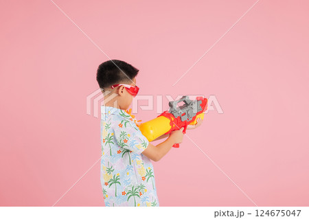 Songkran festival spirit with a back view of a child in a floral shirt holding a water gun 124675047