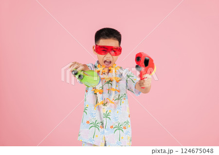 Songkran festival cheer as a happy boy in a floral shirt and glasses holds two water gun 124675048