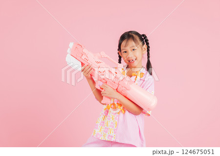 Songkran fun with a happy girl in a floral shirt holding a toy water gun Songkran fun with a happy girl in a floral shirt holding a toy water gun 124675051