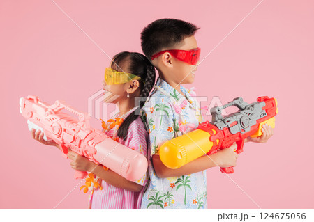 Songkran day as two happy Thai kids, a boy and a girl in glasses, hold plastic water guns together Songkran day as two happy Thai kids, a boy and a girl in glasses, hold plastic water guns together 124675056