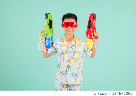 Songkran fun moments with a joyful boy in glasses and a floral shirt holding two toy water pistols Songkran fun moments with a joyful boy in glasses and a floral shirt holding two toy water pistols 124675066