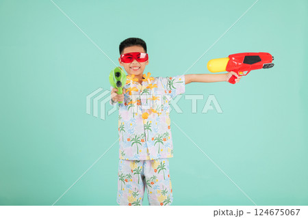 Songkran fun moments with a joyful boy in glasses and a floral shirt holding two toy water pistols 124675067