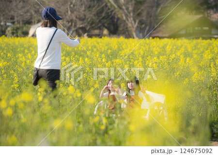 菜の花に囲まれて春を楽しむ姉妹 124675092