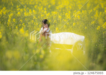 菜の花に包まれて微笑む女の子の春のひととき 124675093
