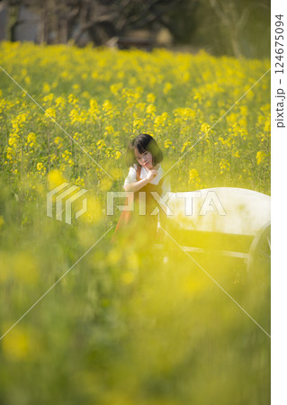 菜の花に包まれて微笑む女の子の春のひととき 124675094