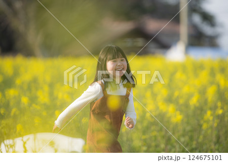 菜の花に包まれて微笑む女の子の春のひととき 124675101