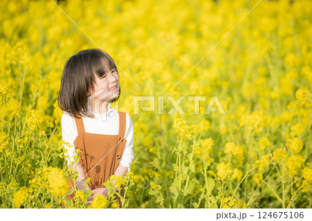 菜の花に包まれて微笑む女の子の春のひととき 124675106
