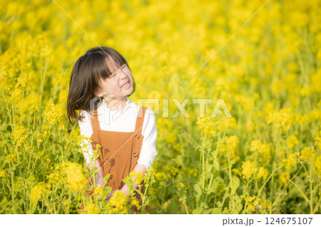 菜の花に包まれて微笑む女の子の春のひととき 124675107