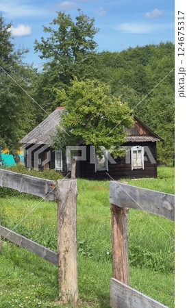 Old wooden house in countryside behind wooden fence during summer sunny day Old wooden house in countryside behind wooden fence during summer sunny day 124675317
