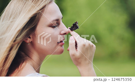 Young blonde woman holding beautiful butterfly on her finger, enjoying nature in a sunny day 124675350