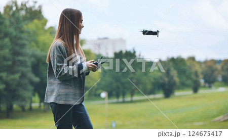 Professional woman piloting drone near park pathway, blending work technology with outdoor leisure Professional woman piloting drone near park pathway, blending work technology with outdoor leisure 124675417
