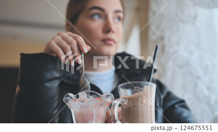 Woman relaxing at cafe, sipping milkshake, enjoying ice cream during quiet afternoon break 124675551