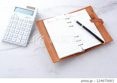 電卓と手帳でデスクワークをしているイメージ 124675661