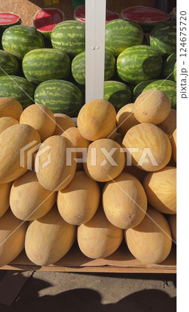 Fresh melons and watermelons displayed on a market stall, creating a vibrant and colorful scene 124675720