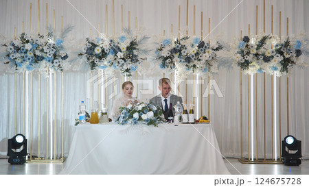 Newlyweds sitting at a decorated table during their wedding reception, enjoying the special moment 124675728