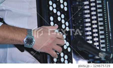Musician's hand performing on vintage accordion, generating festive wedding music with passion and melodic energy 124675729