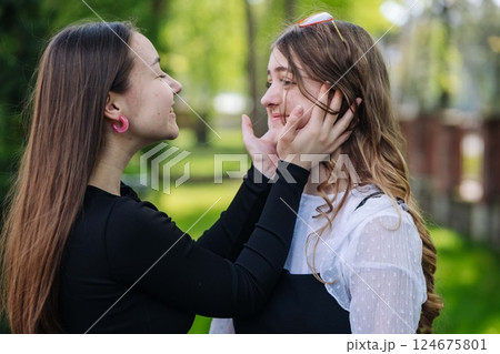 Two teenage girls sharing a moment of affection in the park during a school day, expressing friendship and care 124675801