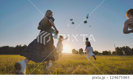 Group of high school students running in a field throwing their notebooks in the air celebrating the end of school year Group of high school students running in a field throwing their notebooks in the air celebrating the end of school year 124675965