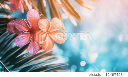 vibrant tropical flowers and palm leaves glowing softly in the sunlight with a dreamy blue bokeh background 124675984