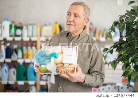 Senior man studies label and choose shower cosmetic present, packaged in basket. 124677444