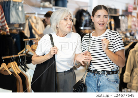 Two women watching excitedly large stock of clothes in clothing store Two women watching excitedly large stock of clothes in clothing store 124677649
